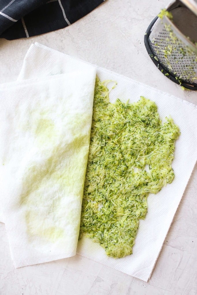 Overhead view of grated zucchini on a paper towel.