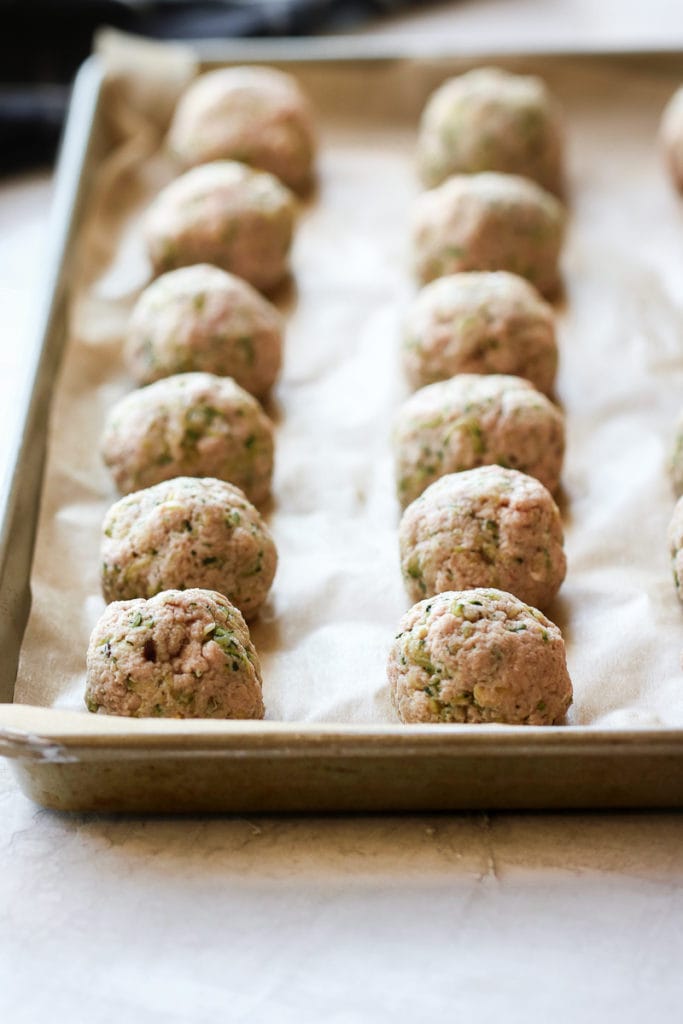 Close up view of Italian Turkey Zucchini Meatballs on a sheet pan ready for baking.