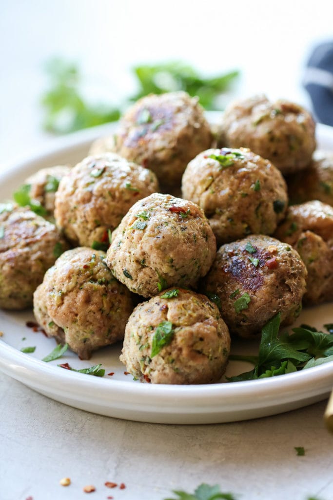 Close up view of a plate of freshly baked Italian Turkey Zucchini Meatballs topped with fresh herbs.