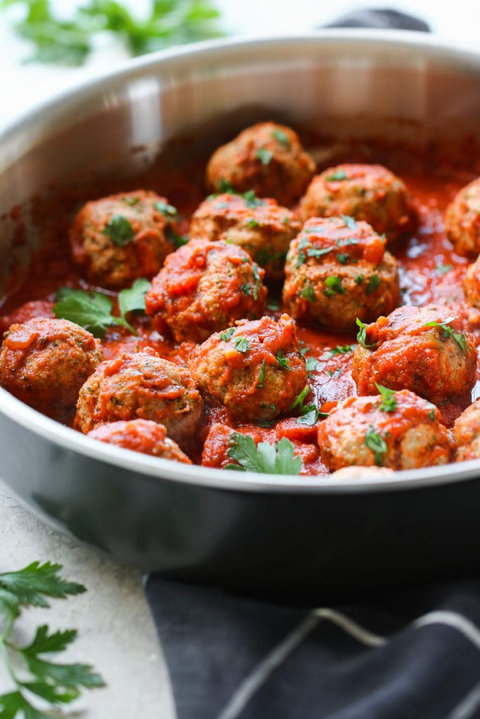 Close up view of Italian Turkey Zucchini Meatballs topped with tomato sauce and fresh herbs.