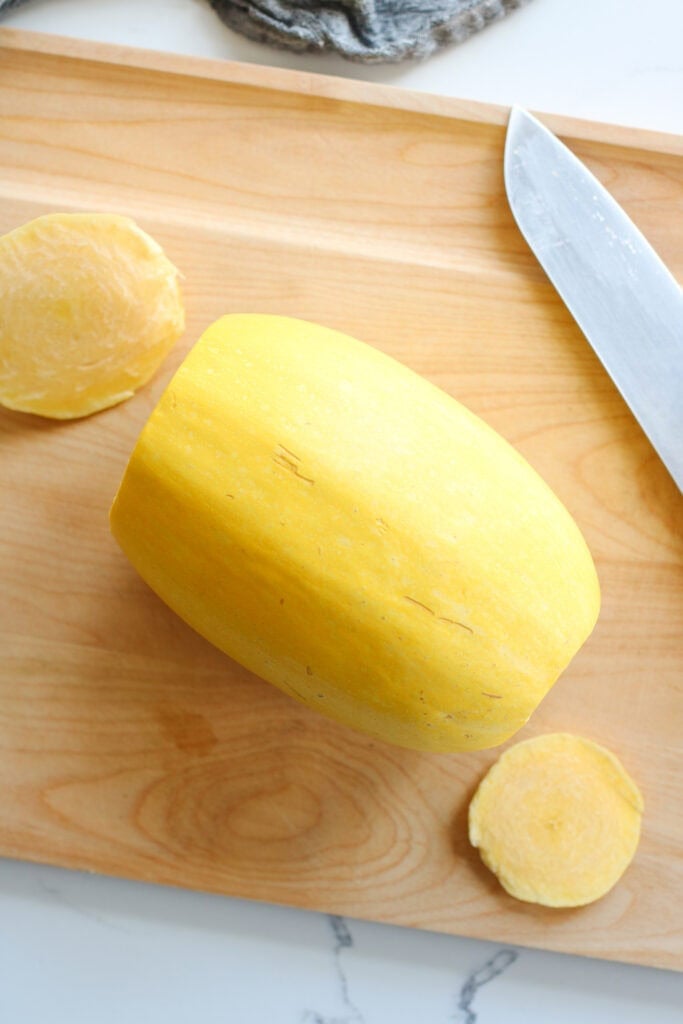 Overhead view of a spaghetti squash with both ends cut off, ready for baking. 