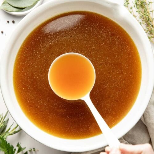 Overhead view of a bowl of bone broth with a spoon bring up a spoonful.