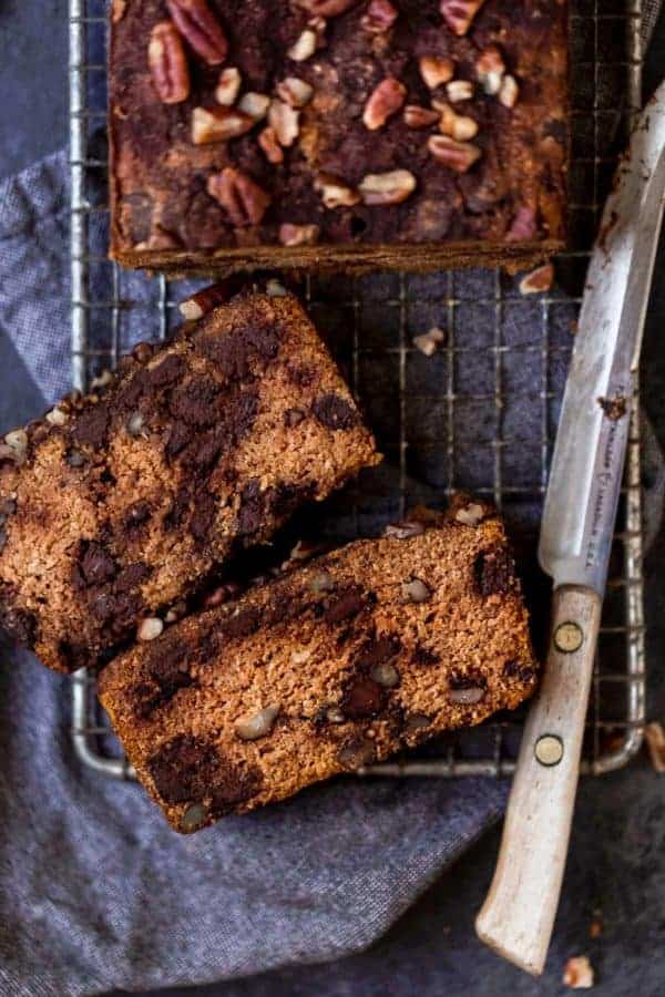 Two slices of healthy paleo pumpkin bread with chocolate chips on on a wire cooling rack.