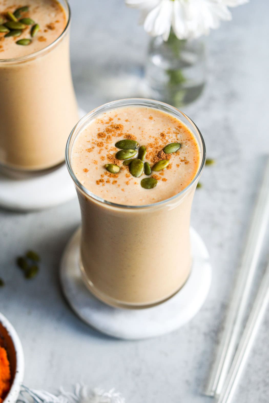 Close up view of a freshly blended Delicious Protein Pumpkin Spice Smoothie topped with cinnamon and pepitas.