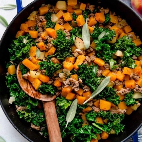 A blue skillet filled with Butternut Squash and Apple Hash with Sausage.
