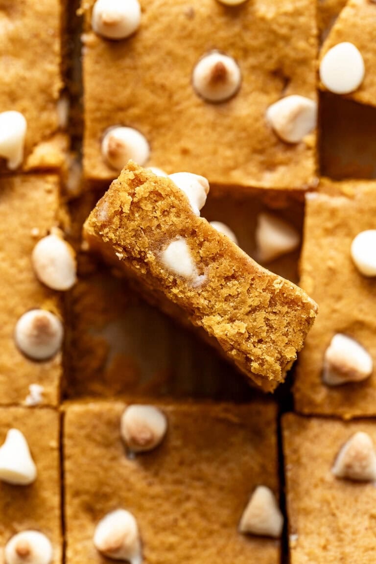 Overhead view of a freshly baked batch of pumpkin blondies studded with white chocolate chips. 