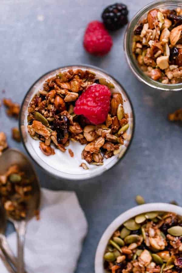 Overhead shot of Paleo Granola in a glass cup on top of yogurt with raspberries and blackberries.