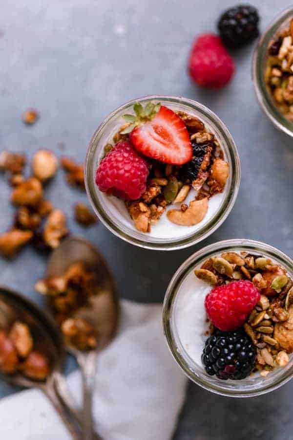 Overhead shot of Paleo Granola in glass cups on top of yogurt with raspberries, strawberries and blackberries.