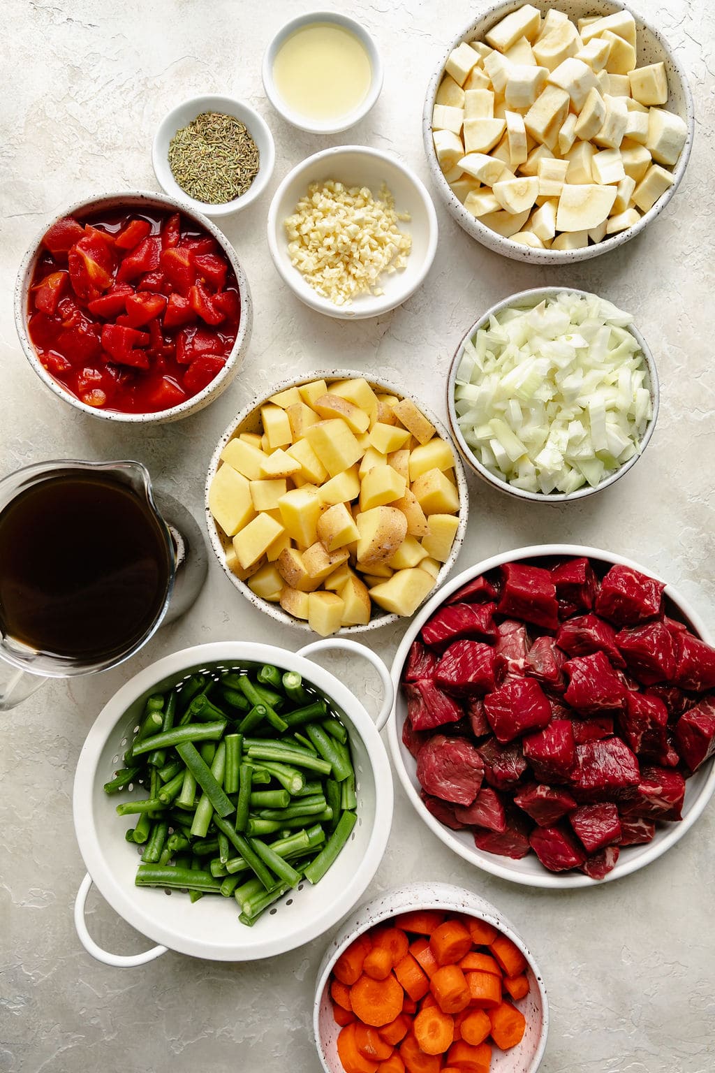 All ingredients for slow cooker beef stew in small bowls 