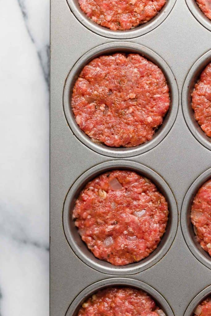 Overhead view of a muffin pan filled with BBQ Meatloaf Muffins mixture ready for baking