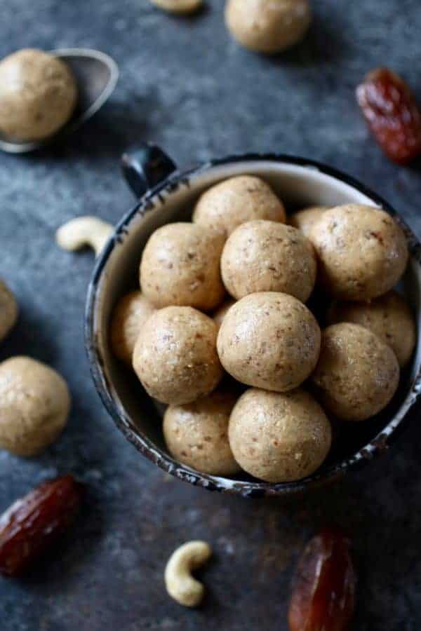 Overhead photo of Nutty Cashew Bites in a white tea cup with dates and cashews surrounding.