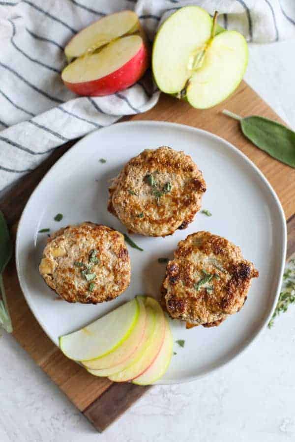 Turkey Apple Sausage Patties on a white plate with apple slices on the side
