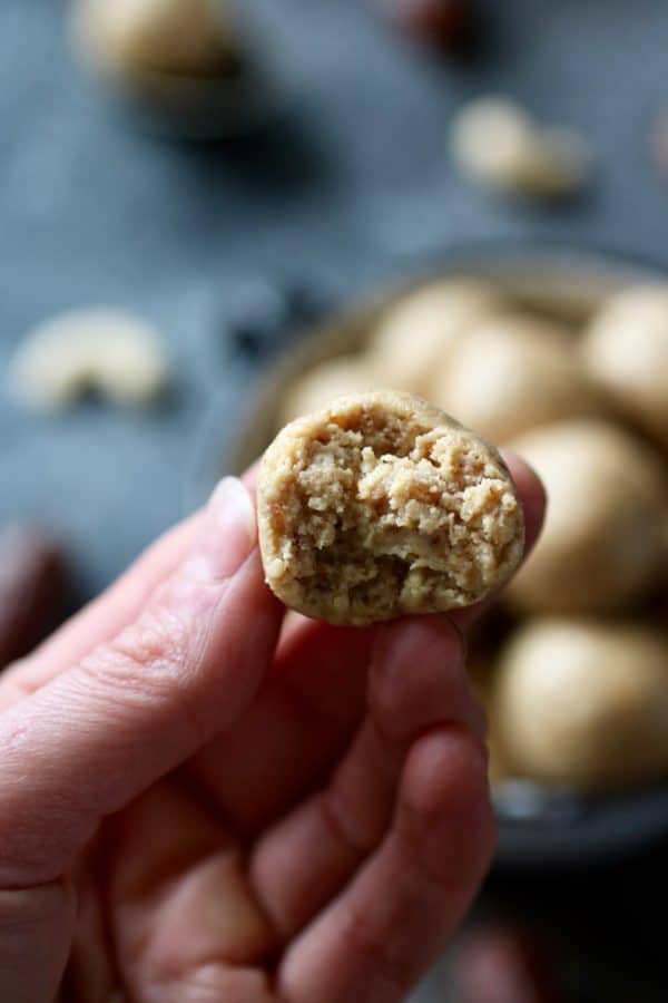 Photo of hand holding one of the Nutty Cashew Bites with a bite taken out of it. 