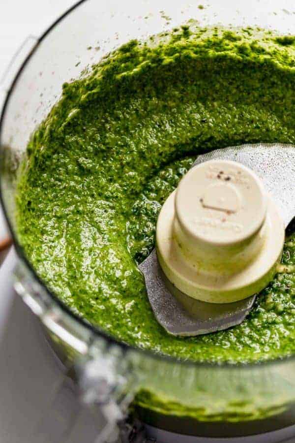 Freshly processed basil walnut pesto in a food processor blender