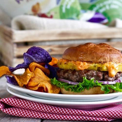 Close up view of a plate with a Bison Burger with Grilled Pineapple and Sriracha Aioli on it