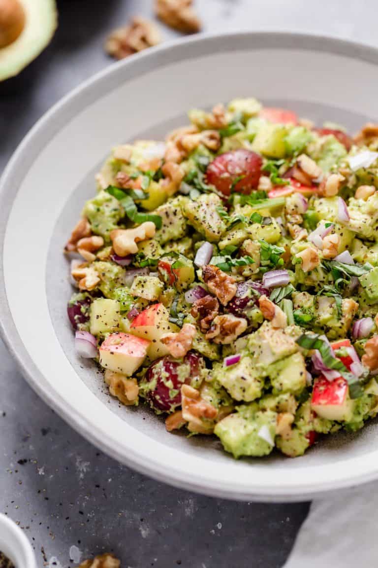Close up view of Avocado Chicken Waldorf Salad topped with red onions and fresh herbs. 