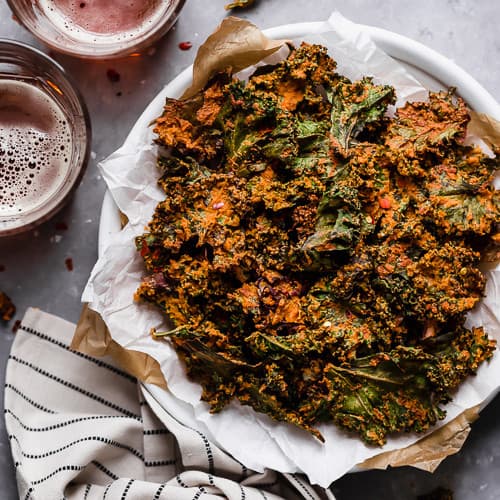 Overhead view of a plate of Cheese Pizza Kale Chips on a white plate