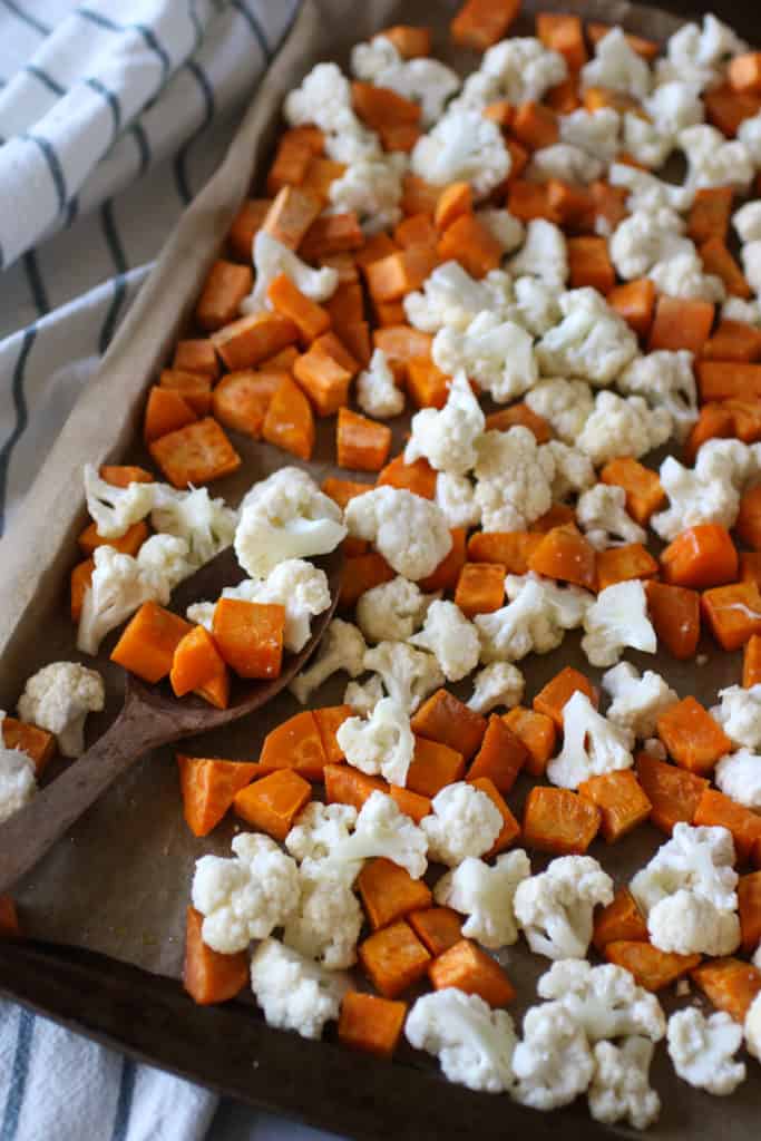 Sweet potato cube and chopped cauliflower on a sheet pan