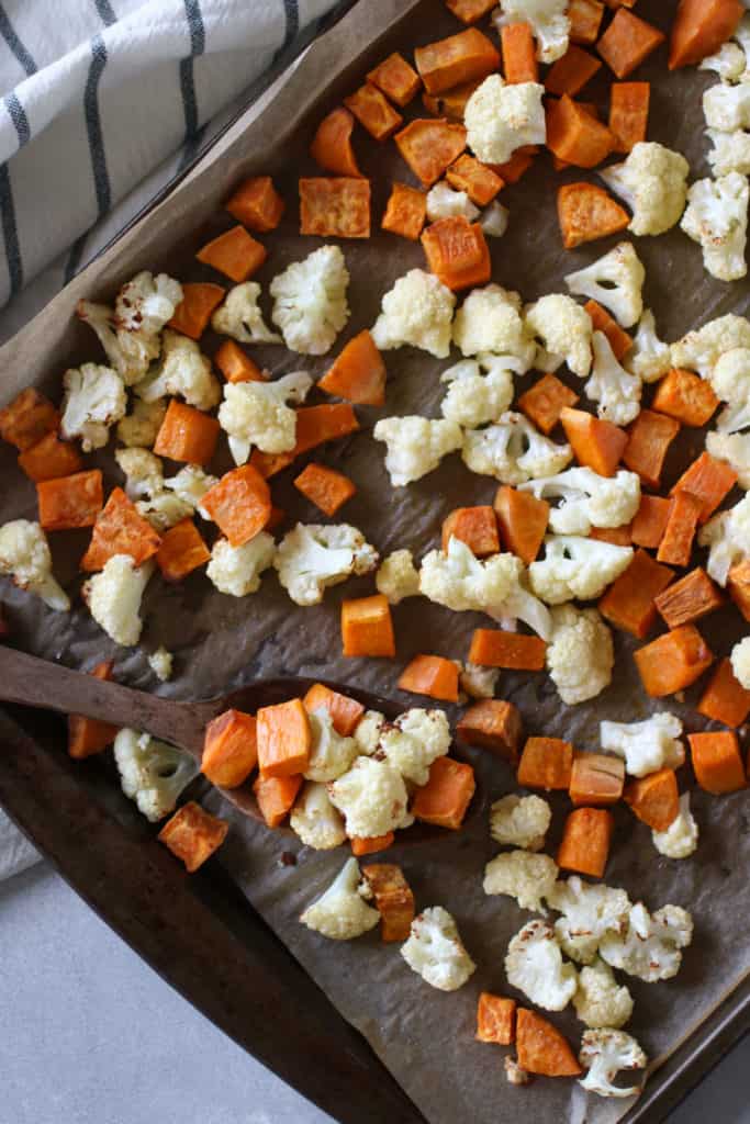 freshly roasted sweet potatoes and cauliflower on a sheet pan