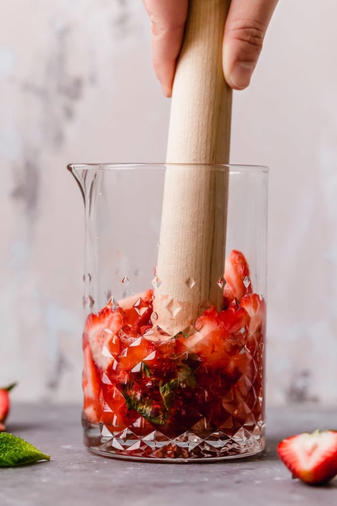 Low-Sugar Strawberry Mojito Kombucha Cocktail ingredients being combined in a glass pitcher