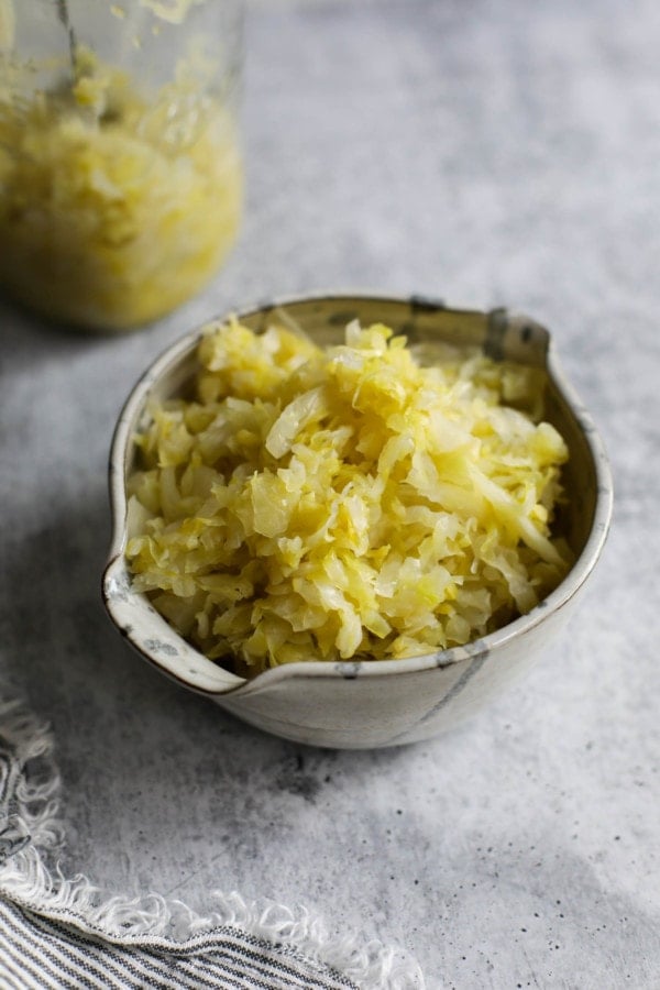 A ceramic bowl on a table filled with homemade sauerkraut.