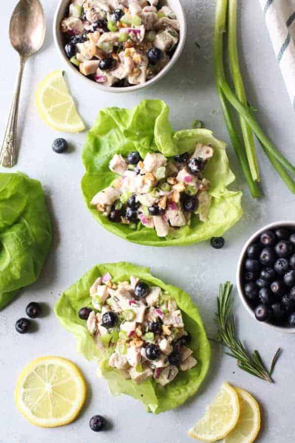 Blueberry Chicken Salad with Rosemary in two lettuce wraps with additional salad in a white bowl