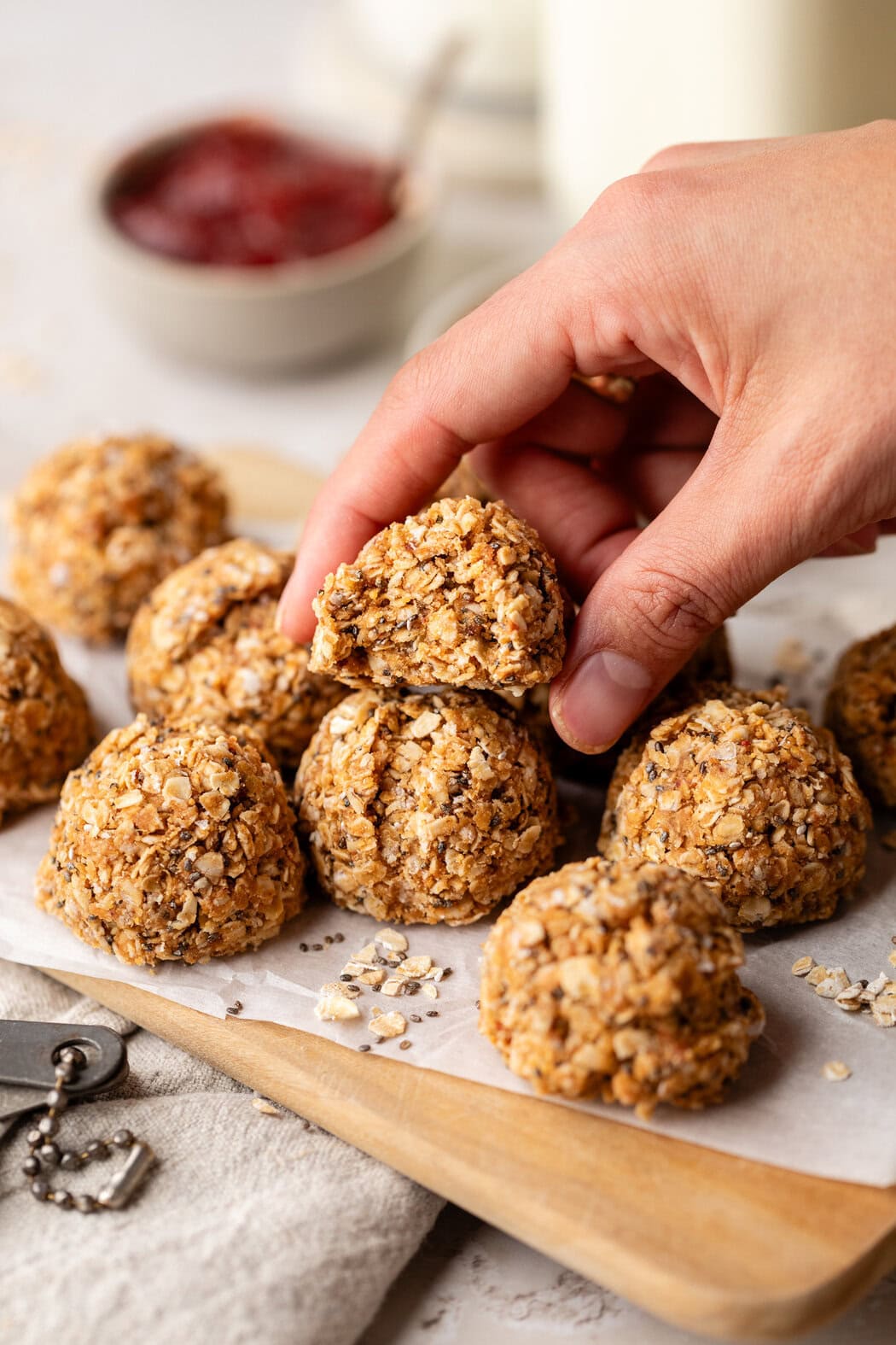 A hand grabbing a No-Bake PB & J Bite from a group of them on parchment paper. 