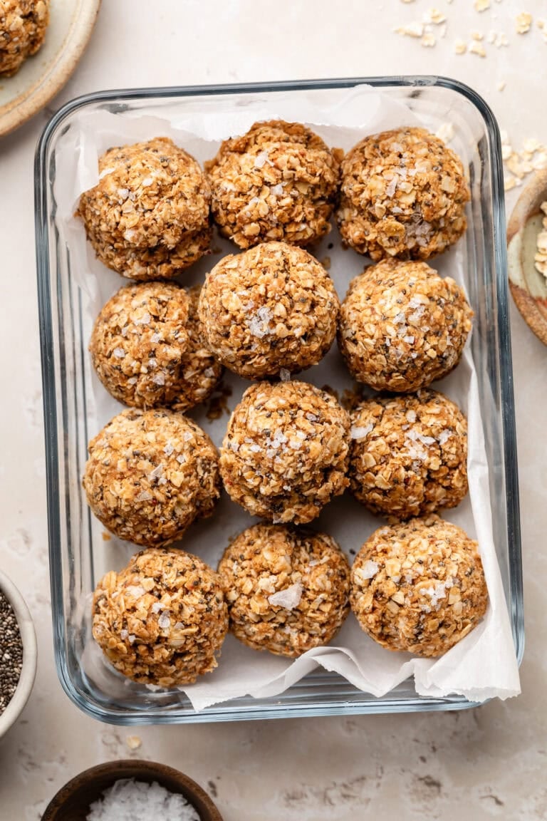 Overhead view of a glass meal prep container filled with PB & J bites sprinkled with flakey sea salt.