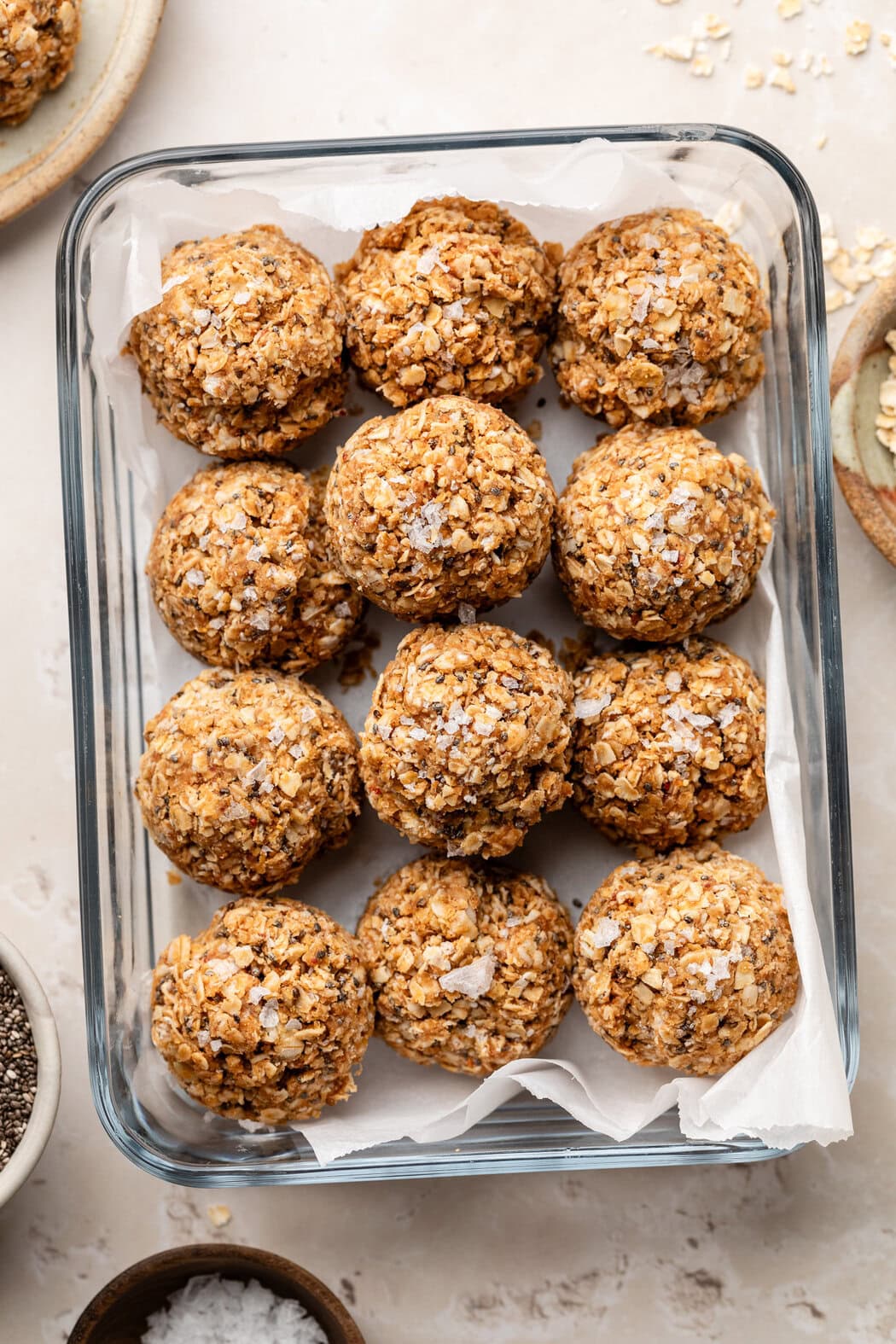 A glass meal prep container filled with No-Bake PB & J Bites and topped with flakey sea salt. 