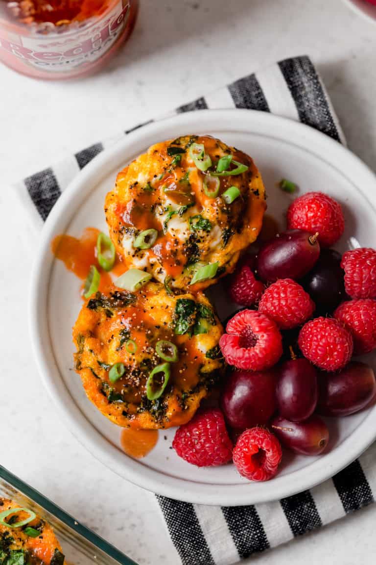 A plate of buffalo chicken egg muffins with fresh berries. 