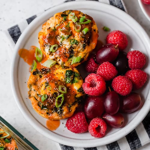 Overhead view of a plate of Buffalo Chicken Egg Muffins with fresh berries