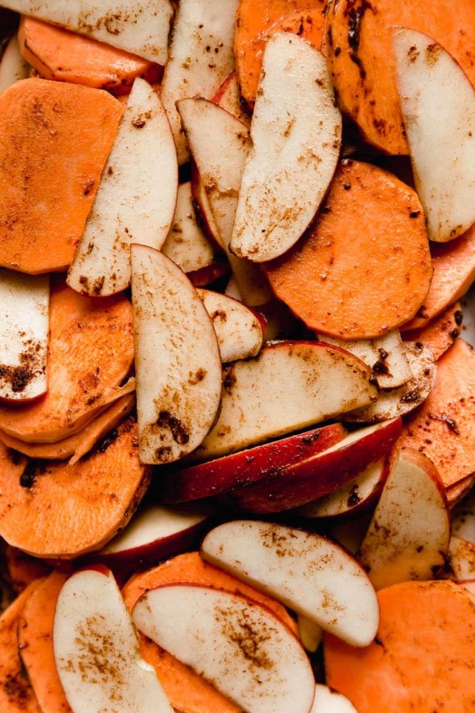 Close up view sliced sweet potatoes and apples coated in butter and cinnamon