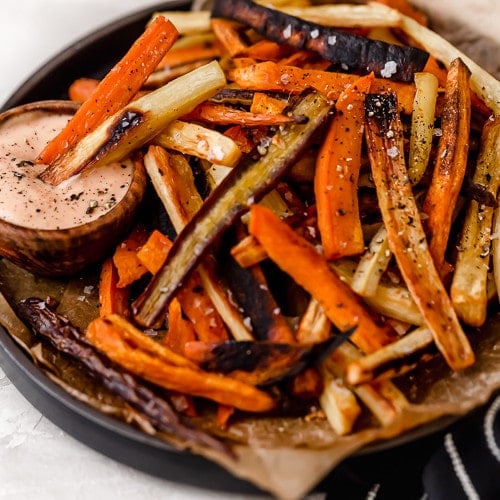Plate of garlic roasted root vegetable fries with a side of chipotle-lime mayo for dipping.