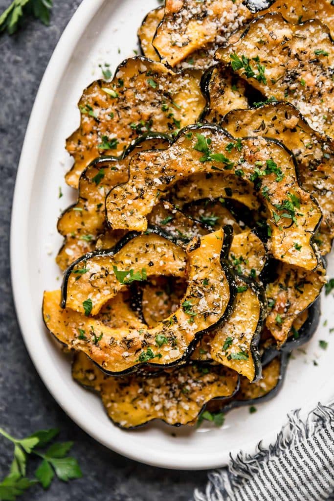 Parmesan coated acorn squash pieces on a platter for a Thanksgiving menu