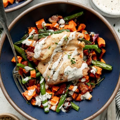 Overhead view blue bowl with serving of chicken bacon ranch served over roasted vegetables.