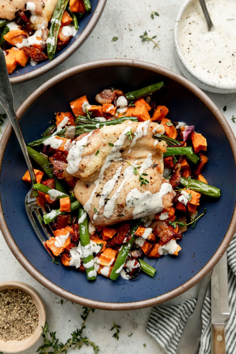 Overhead view blue bowl with serving of chicken bacon ranch served over roasted vegetables.