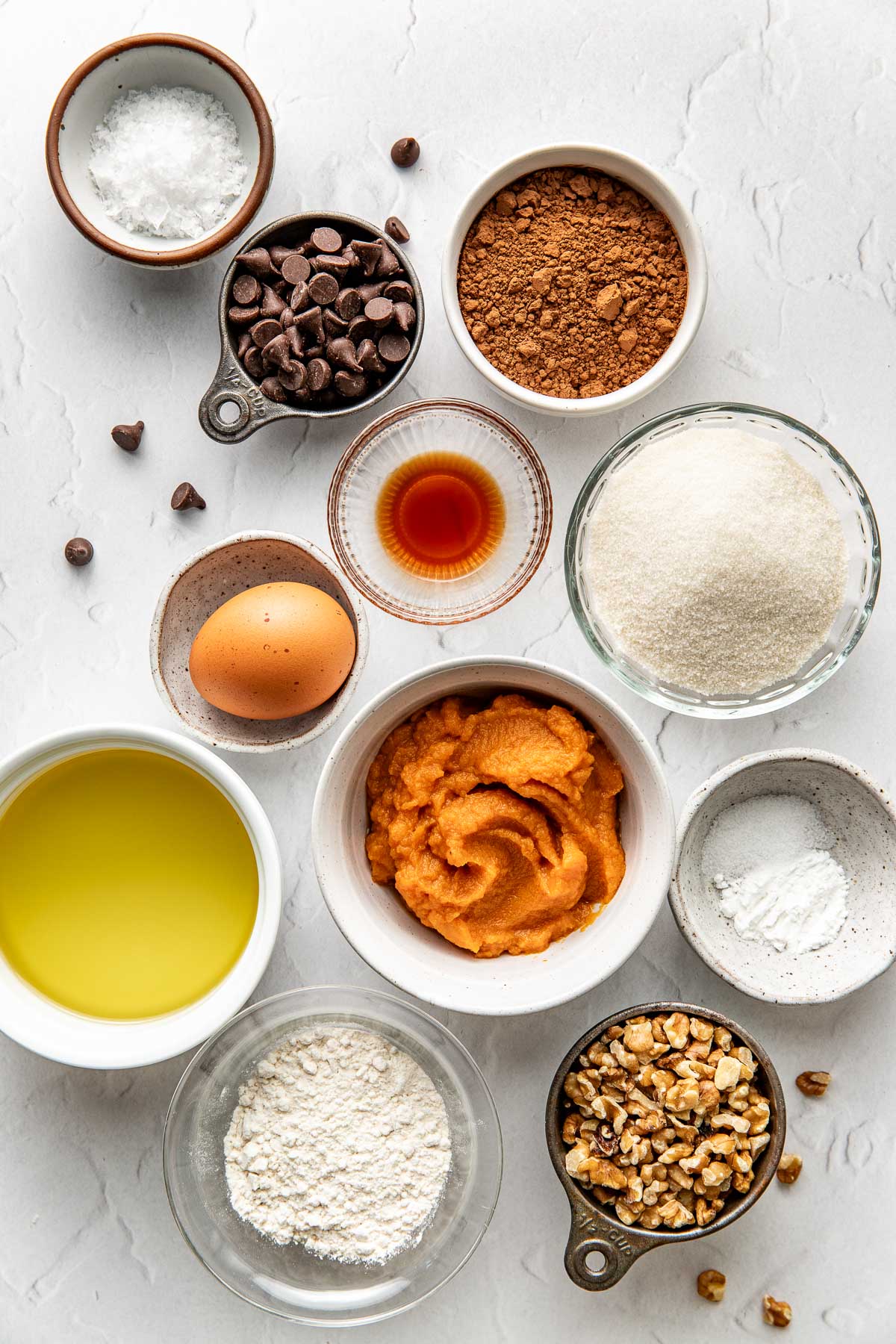 Overhead view of a variety of ingredients for sweet potato brownies in different sized bowls. 