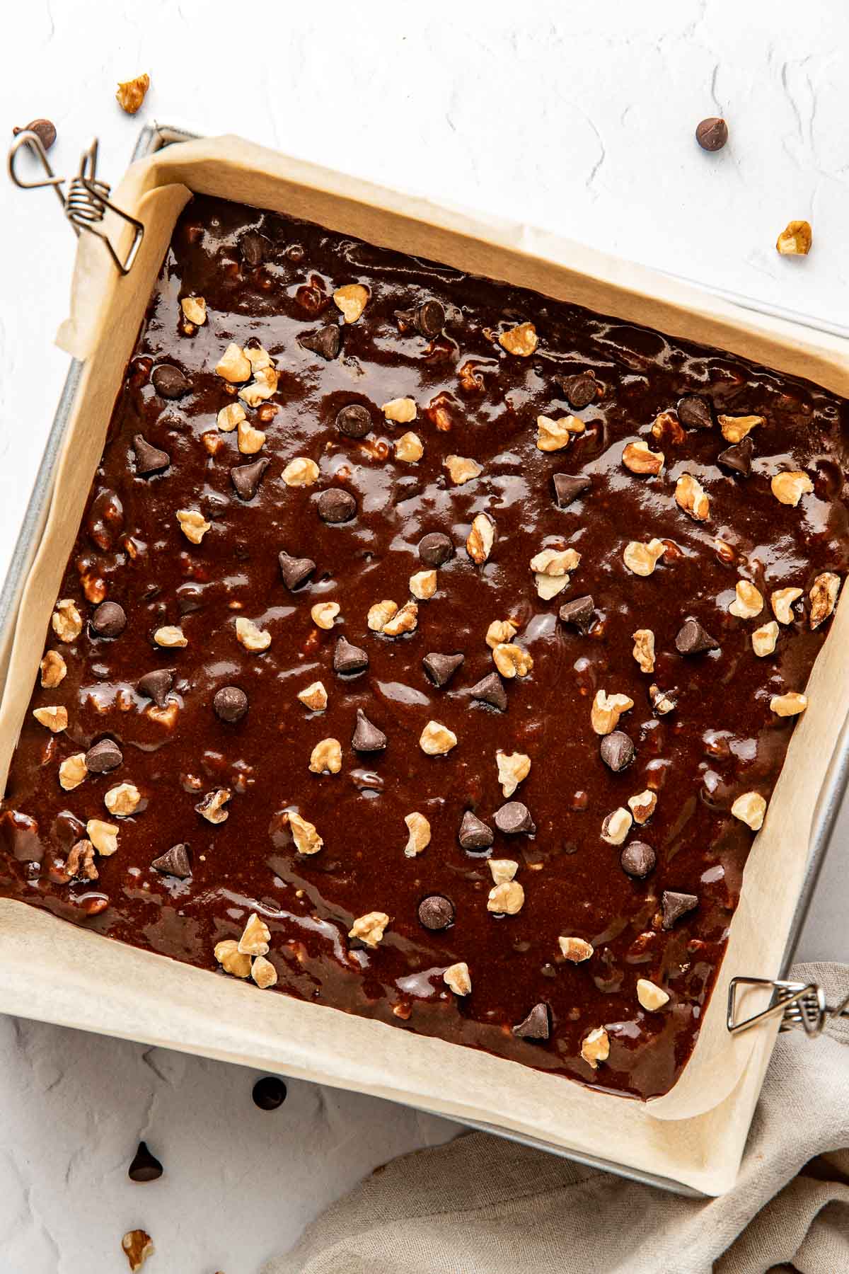 Overhead view of a pan lined with parchment paper and filled with sweet potato brownie batter. 