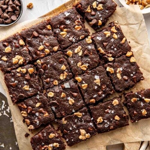 Overhead view of freshly baked sweet potato brownies on a wooden cutting board topped with nuts.