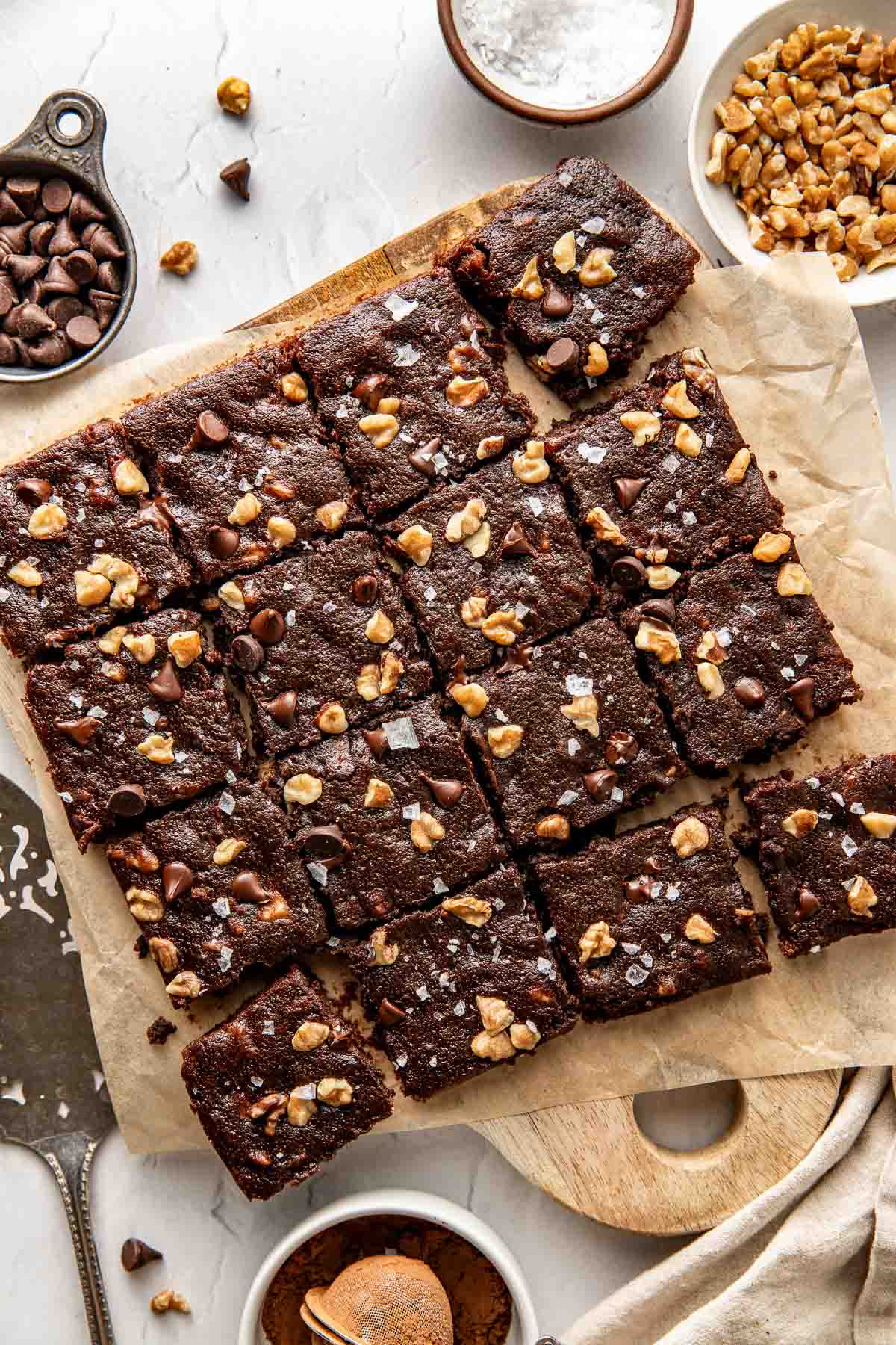 Overhead view of a freshly cut batch of sweet potato brownies topped with flakey sea salt and pieces of nuts. 