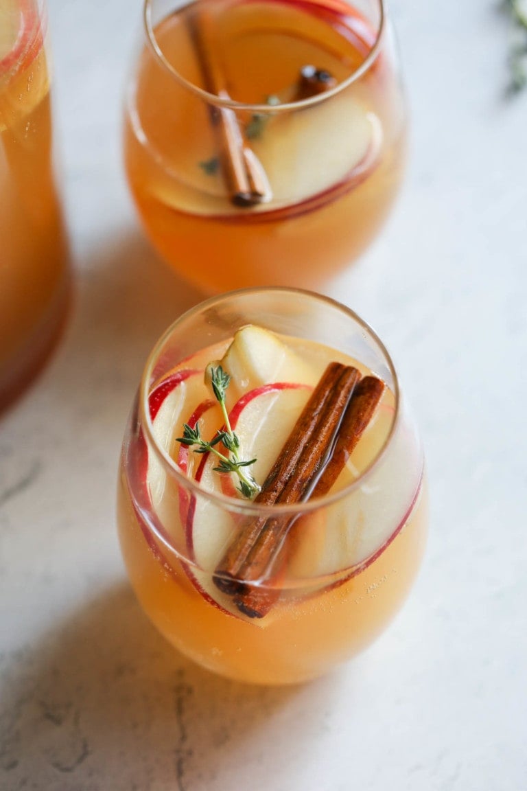 Glasses of apple cider sangria with apple slices and cinnamon sticks on top. 