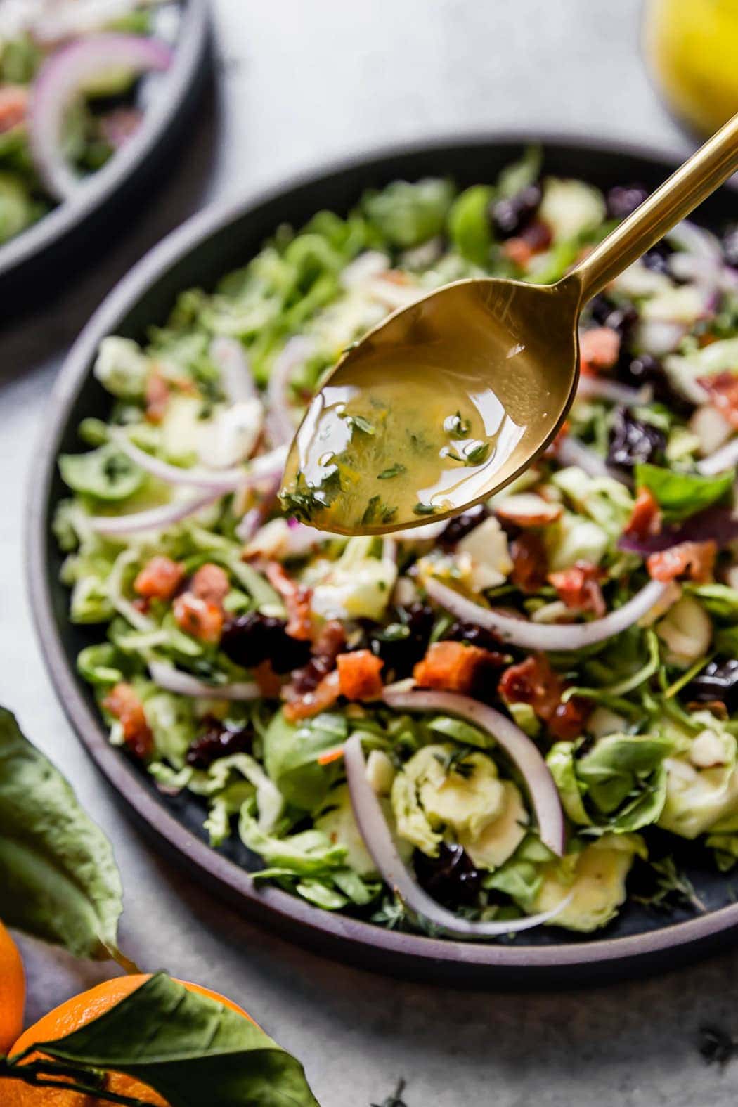 Brussels Sprouts Salad with Citrus Vinaigrette and a spoon drizzling dressing on the top