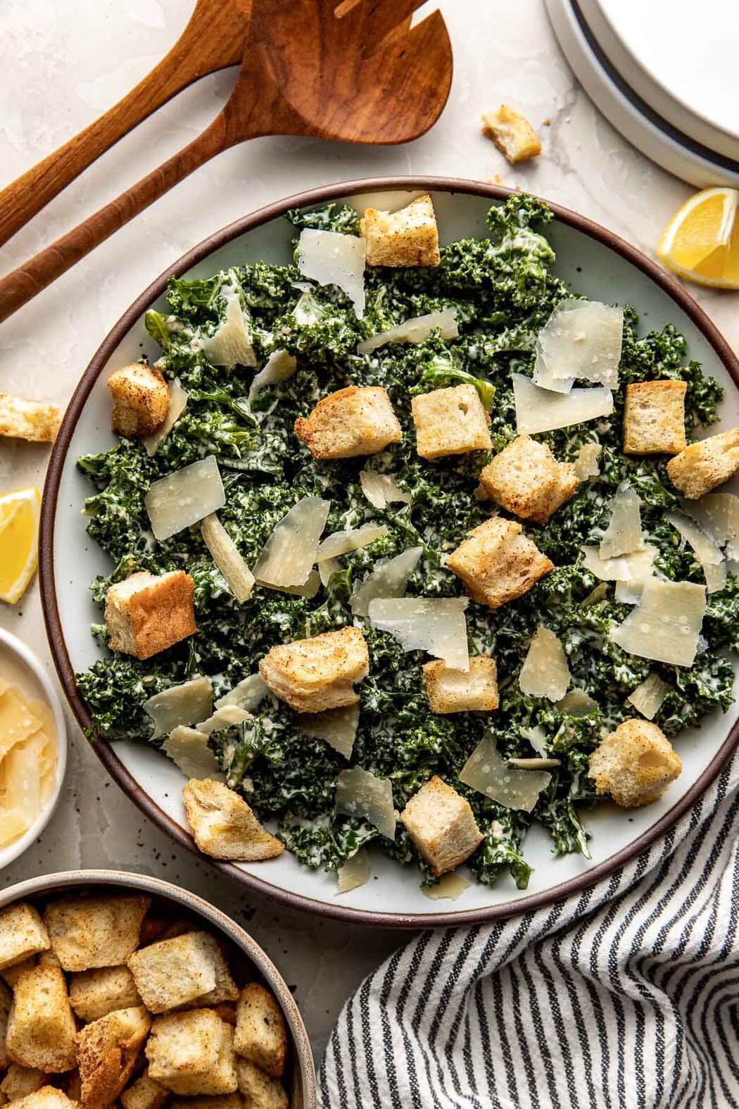 Overhead view of a bowl filled with Kale Caesar Salad topped with shaved parmesan and garlic croutons.
