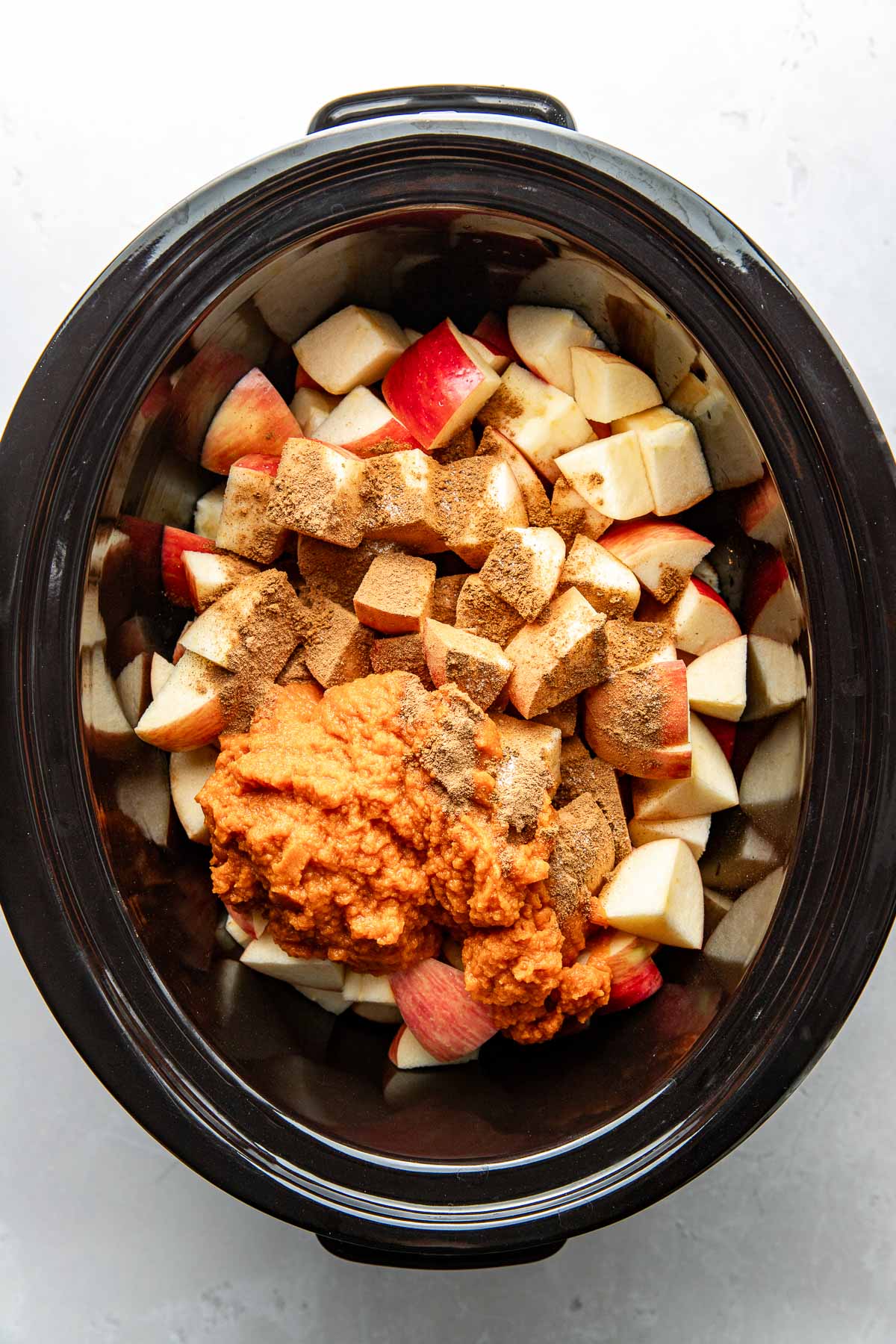 Overhead view of a slow cooker filled with Crockpot Pumpkin Applesauce ingredients.