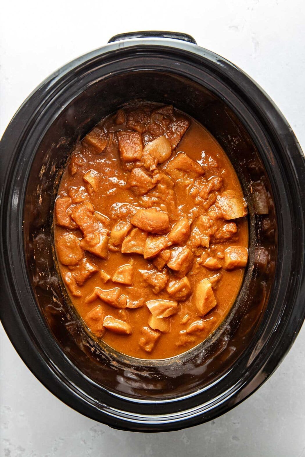 Overhead view of a slow cooker filled with Pumpkin and apples ready to be blended into applesauce.