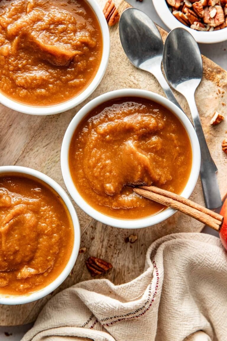 Overhead view of small bowls of slow cooker pumpkin applesauce with a cinnamon stick stuck into the bowl. 