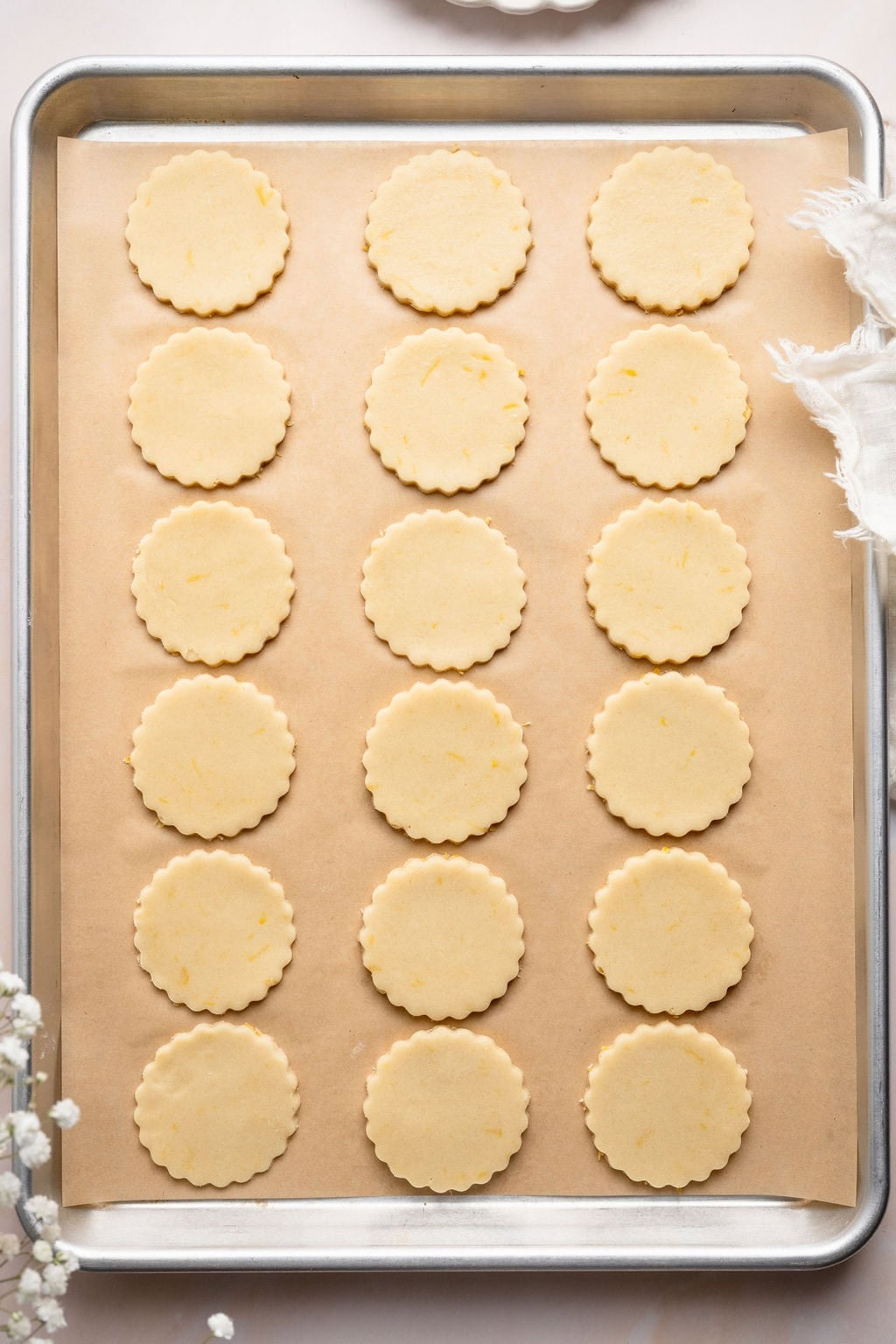 Overhead view of a sheet pan filled with lemon cookie dough cut outs ready for baking. 