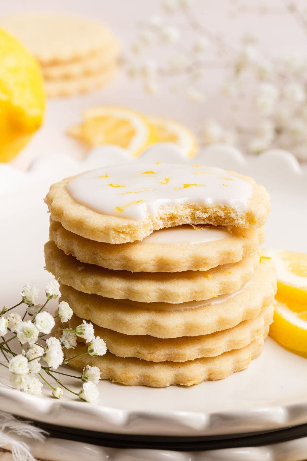 Close up view of a stack of lemon cookies with the top cookie showing a bite mark out of it. 