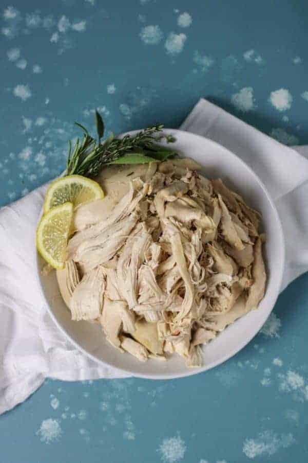 Overhead view of a white plate of Instant Pot Whole Chicken with lemon slices on the side