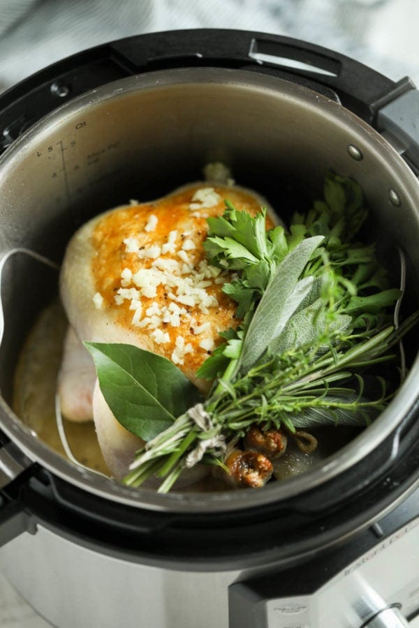 A whole chicken that has been browned and sprinkled with minced garlic and topped with a bouquet of fresh herbs. 